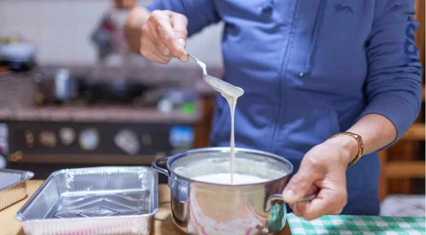 Klasyczna wegetariańska lasagne w Bolonii we Włoszech; Do formy wlewa się kilka łyżek gotowego sosu beszamelowego