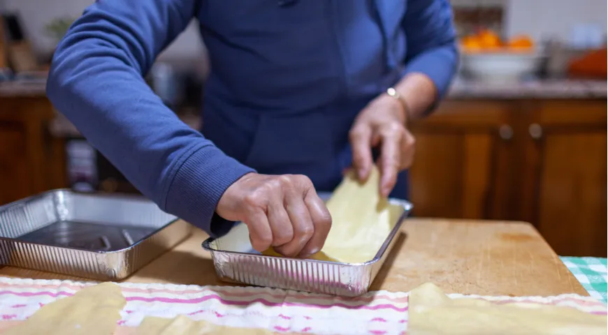 Klasyczna wegetariańska lasagne w Bolonii we Włoszech; Rozpoczyna się składanie lasagne, po sosie przychodzi makaron