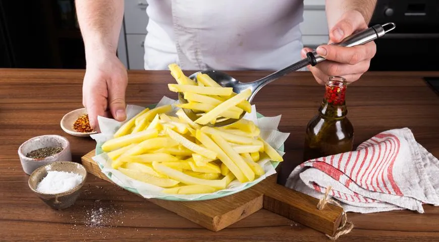 Gotowe ziemniaki ułóż na ręcznikach papierowych, odsącz i posyp solą.